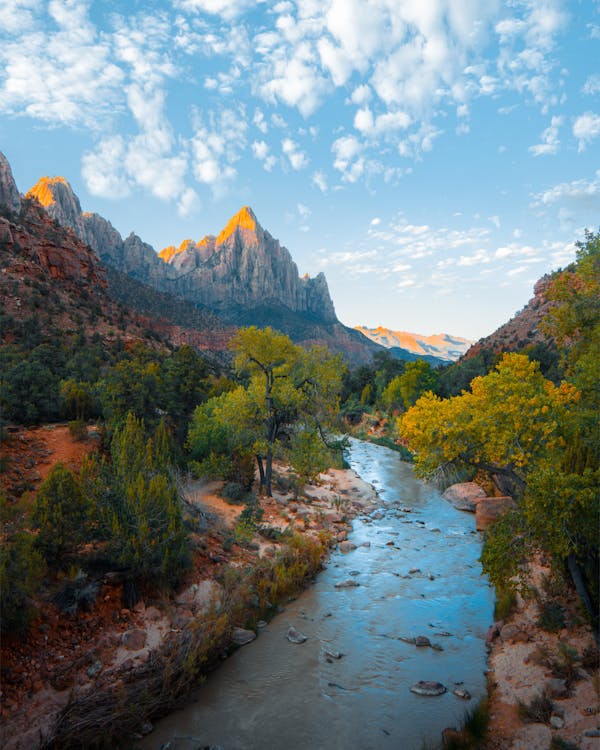 Landscape of mountains with river running through the valley and tress on the river bank.